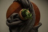 A cozy nook featuring a woven basket filled with blankets and a small succulent on a wooden stool.