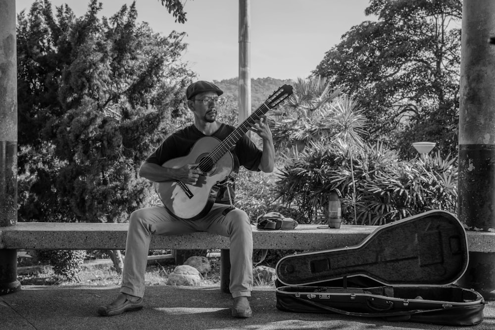 grayscale photography of man playing classic guiar