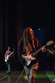 A close-up of a guitarist playing reggae music on stage.