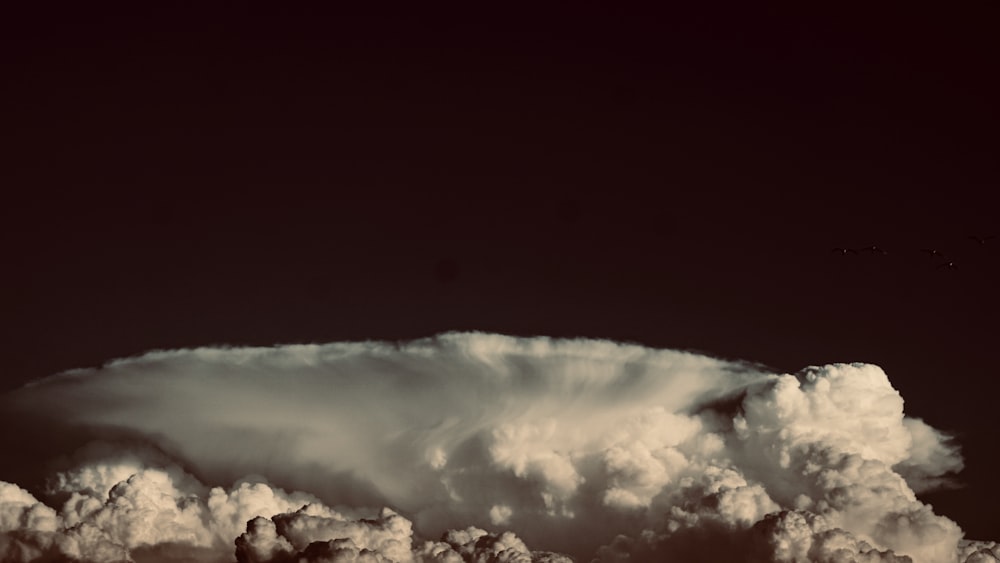 a very large cloud in the middle of a black sky