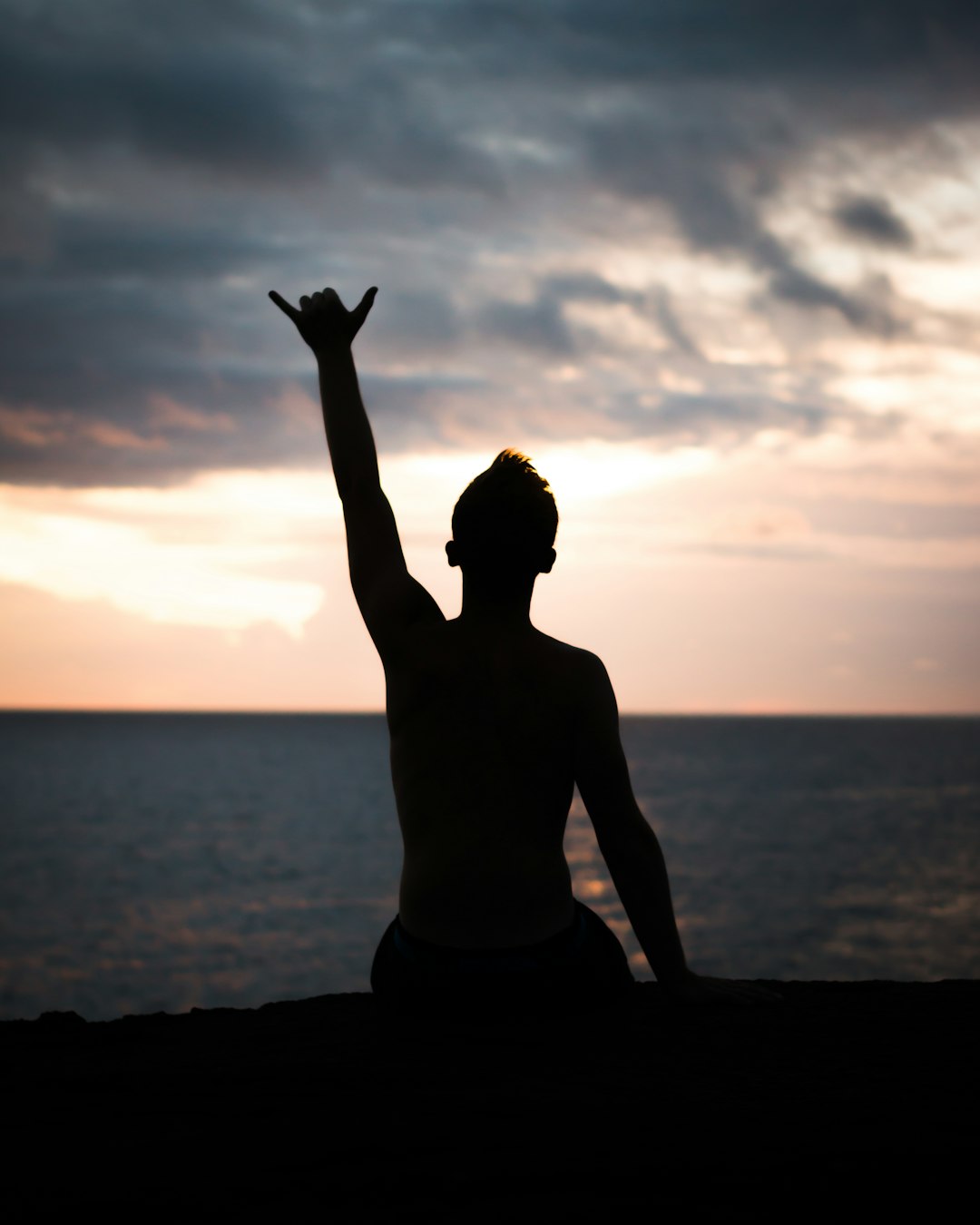 silhouette of person raising hands near shore