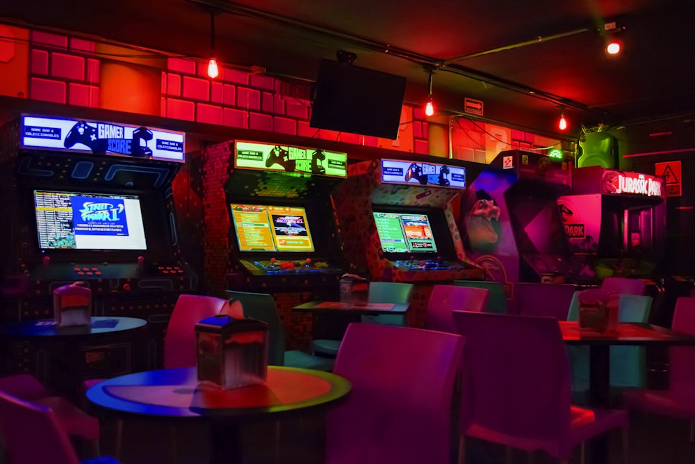 arcade machines near tables and chairs in dim-lit room