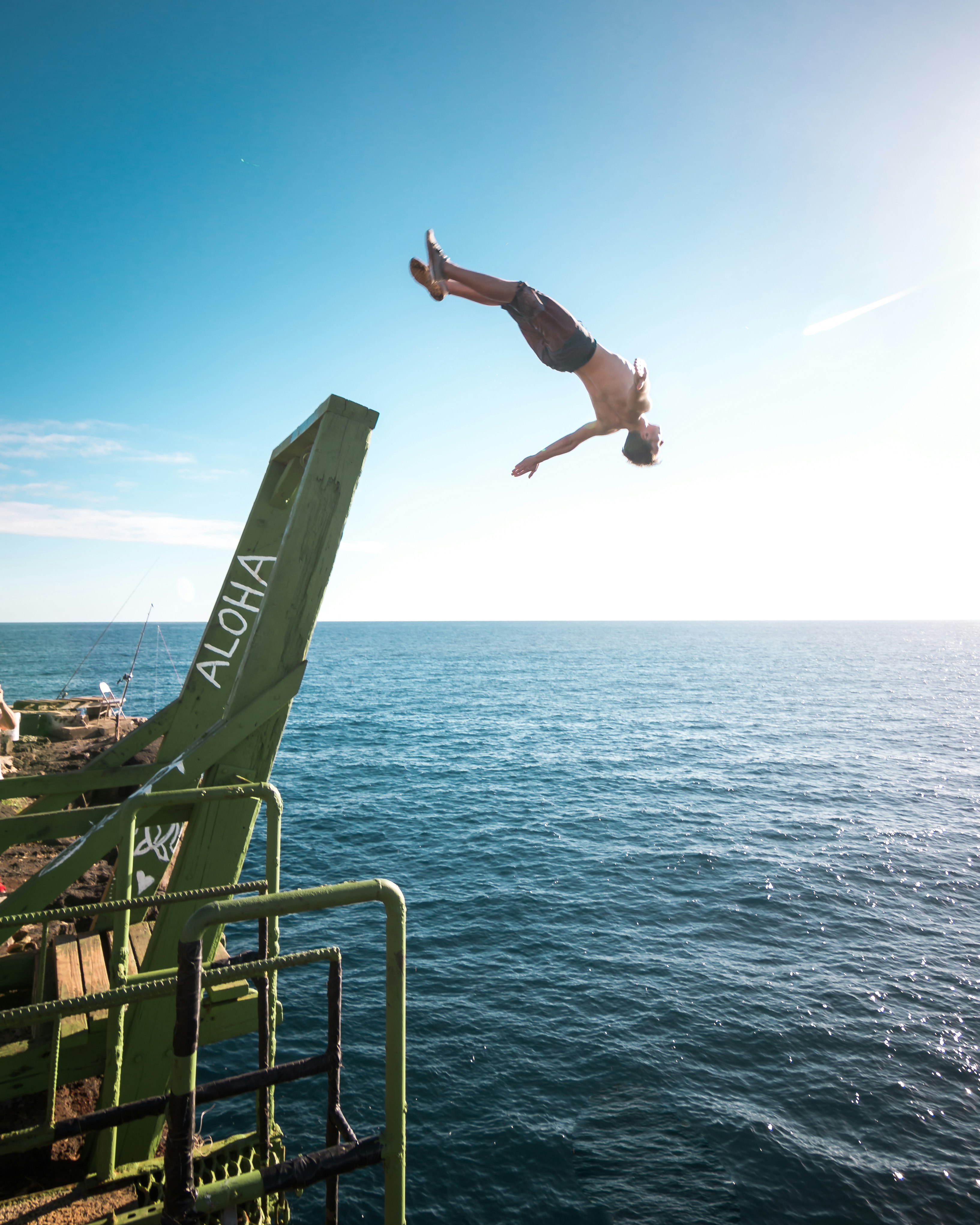 person jump on body of water during daytime