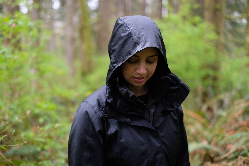 森の中で地面を見つめながら佇む女性