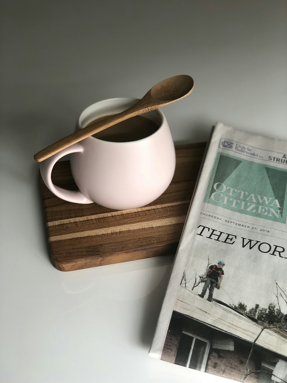 filled white ceramic mug and newspaper on white surface