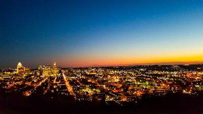 A city skyline at dusk, illuminated by city lights.