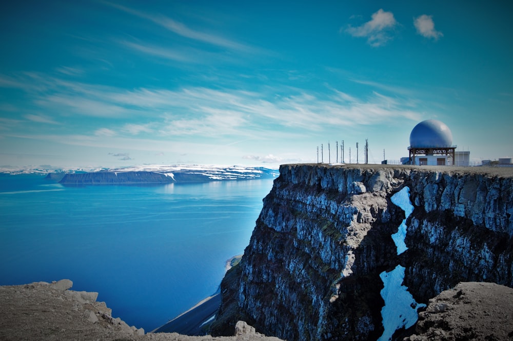 white dome building near edge of cliff overlooking body of water at daytime