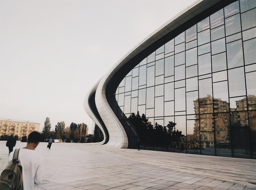 Mann blickt vor einem glasartigen Gebäude im Slide-Stil nach unten