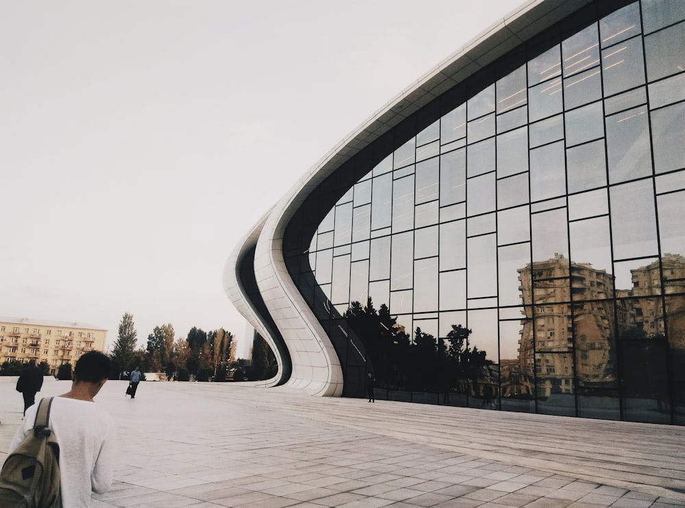 man looking down in front of slide-style glass building