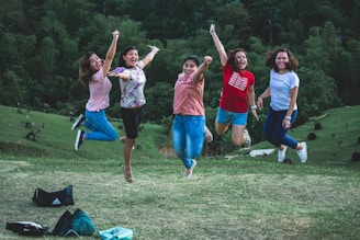 A group of happy customers taking off together from a grassy hilltop.