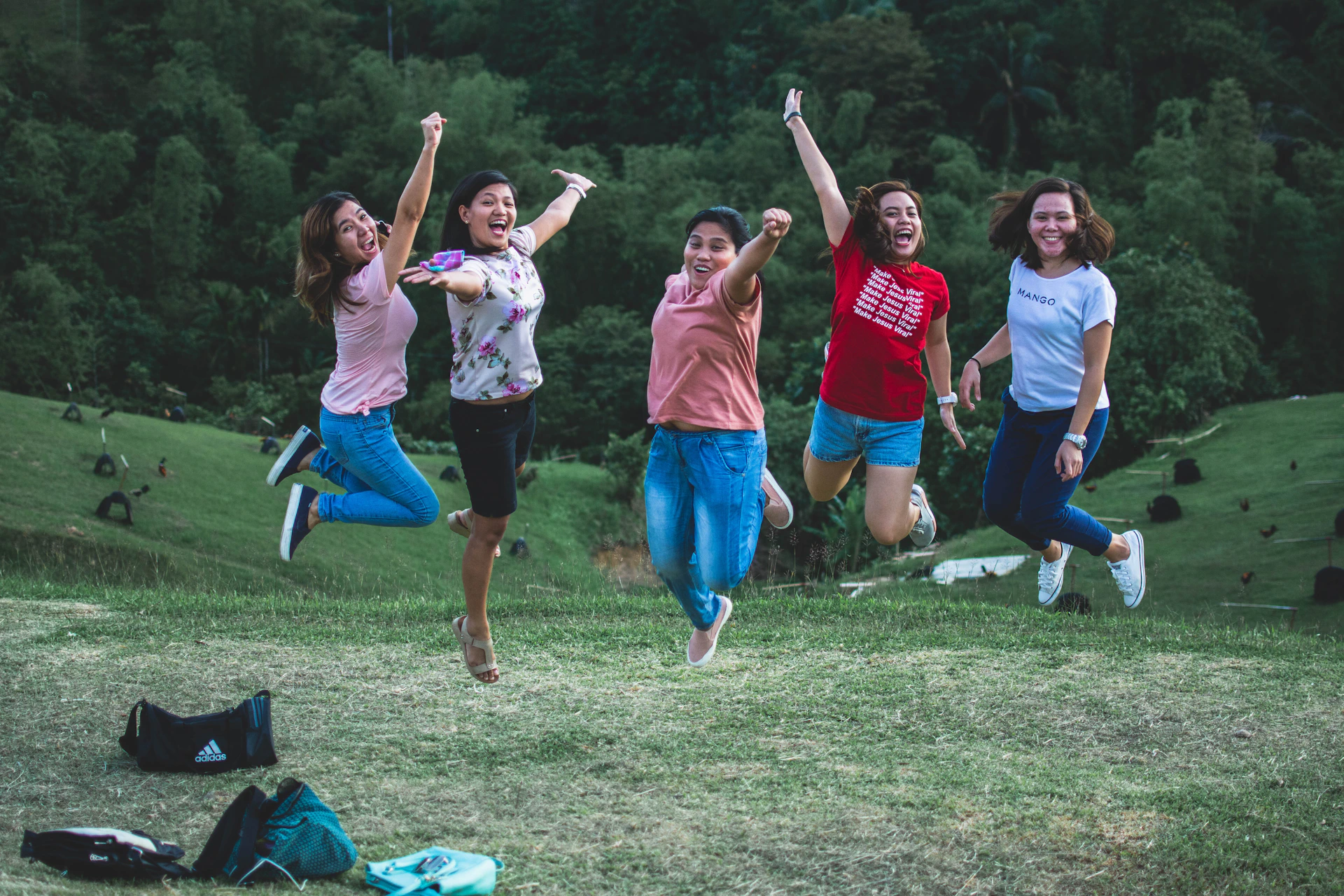 five women jumping on green grass