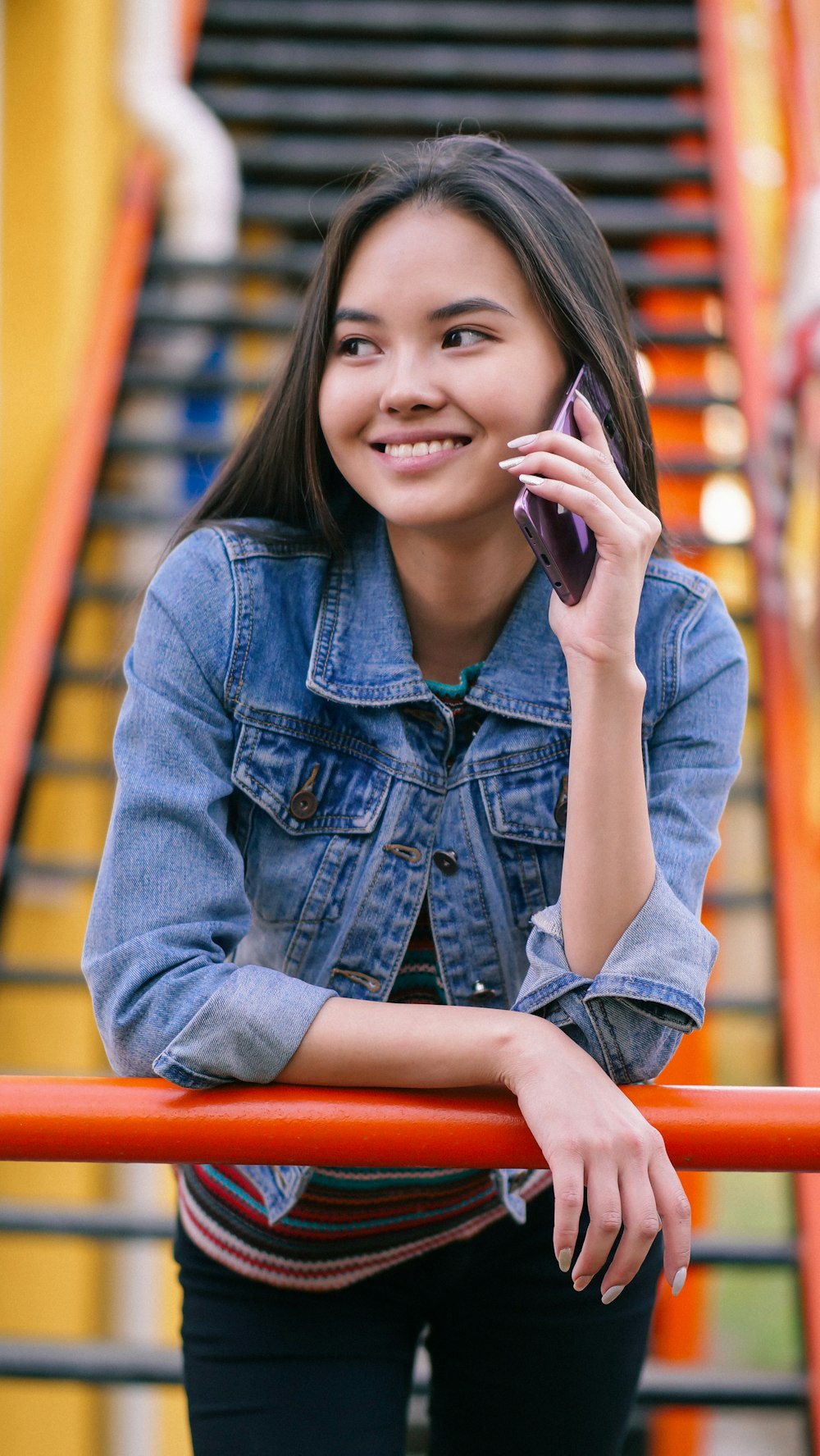 woman leaning on red handrail while using phone