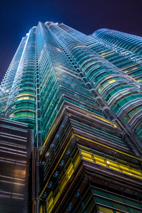 A sleek, modern skyscraper in Baghdad bathed in royal navy blue and emerald green lighting, symbolizing growth and opportunity.