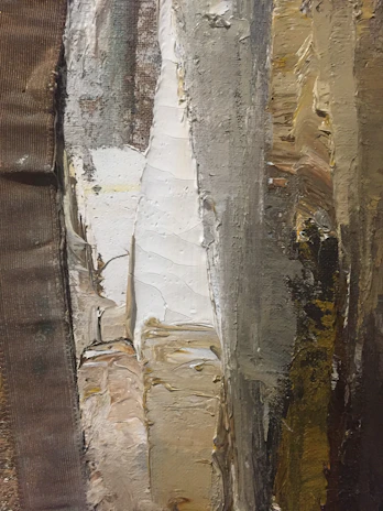 A towering vertical painting with thick, textured impasto in muted earth tones against a light concrete-grey background.