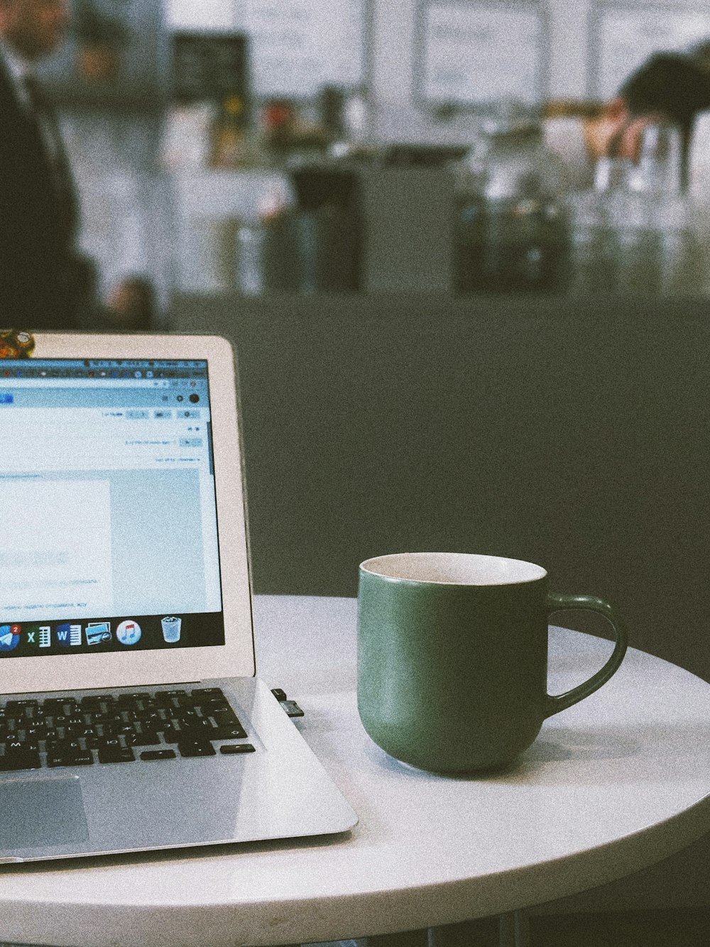 green mug beside MacBook