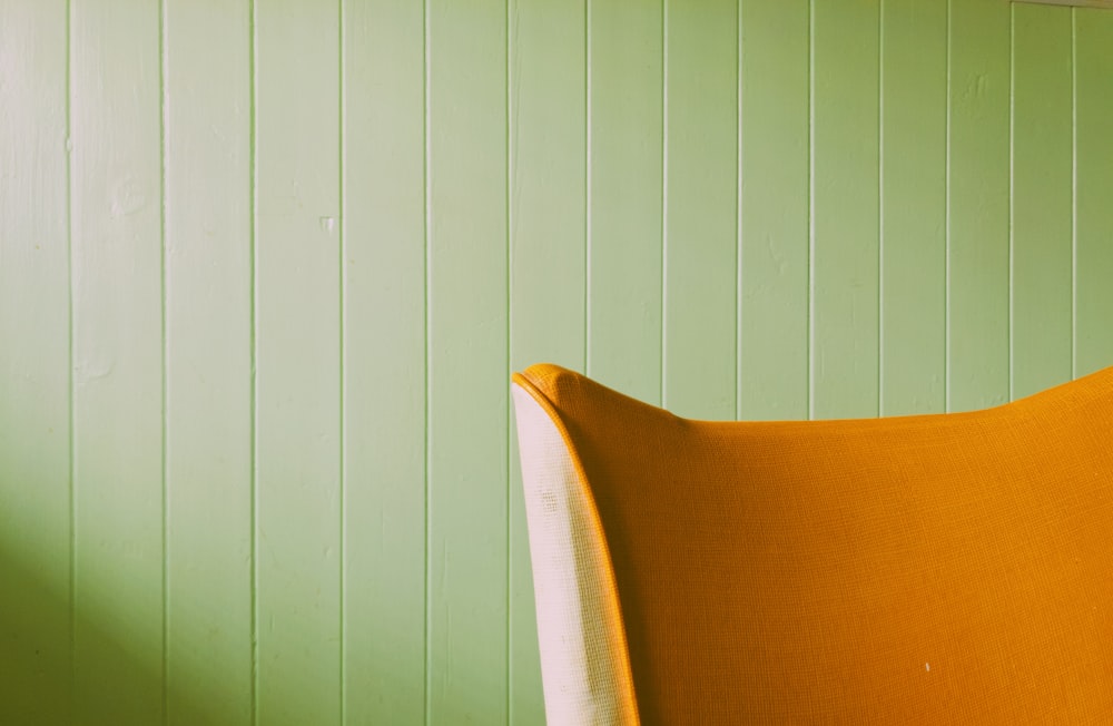 a yellow chair against a green wall in a room