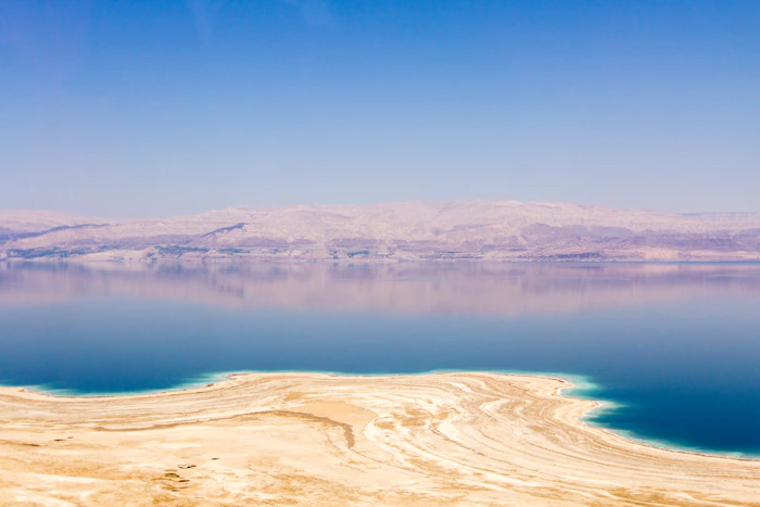 Salt-white shoreline of the Dead Sea with mountains beyond