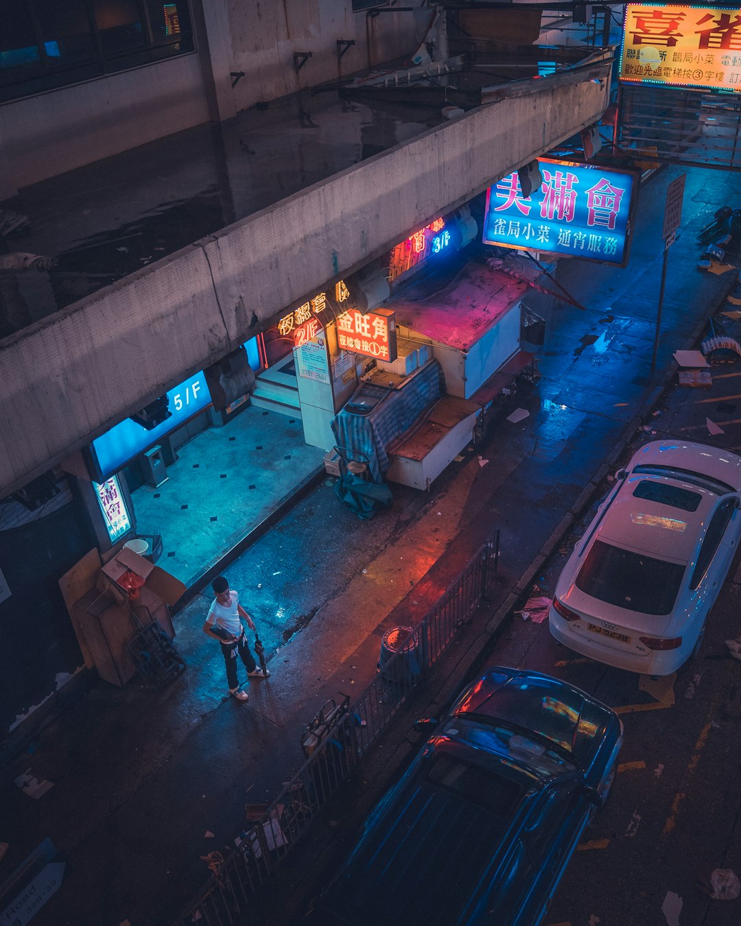 man in white t-shirt standing near parked cars