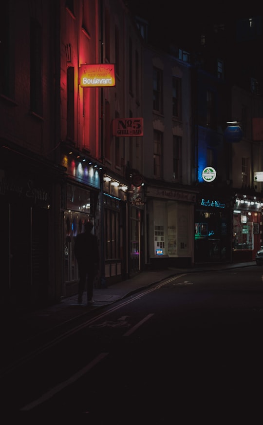 person walking under lighted signage at night in Bristol United Kingdom
