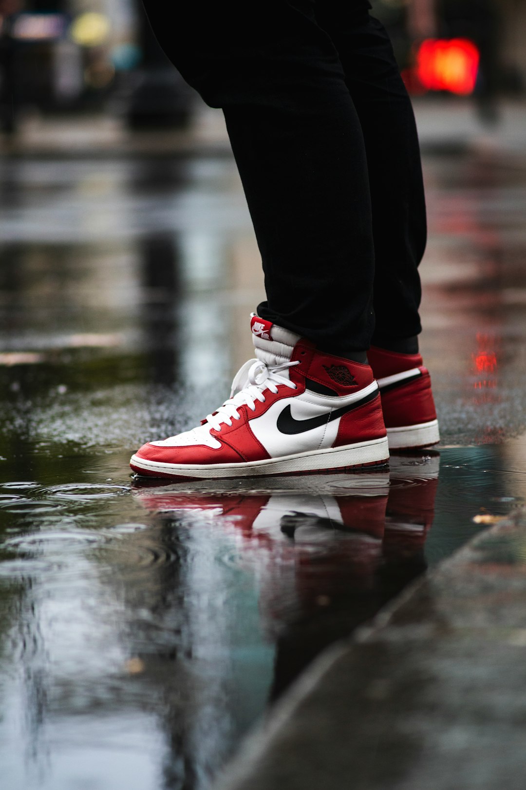 selective focus photography of person wearing white-red-and-black Air Jordan 1's Chicago