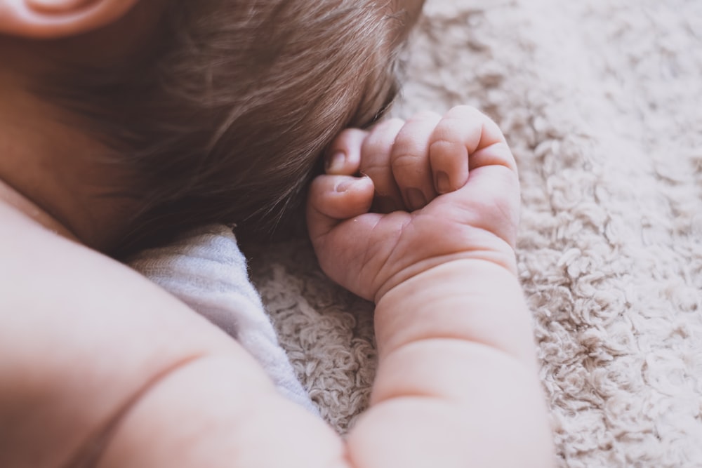 newborn baby lying down on brown blanket