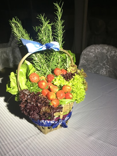 A rustic wicker basket filled with fresh fruits and flowers on a wooden table.