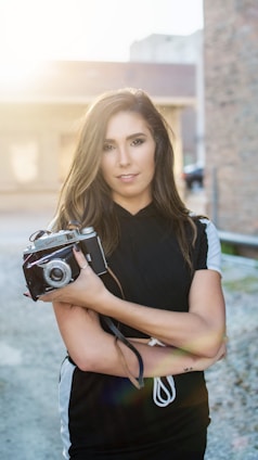 Portrait of Gasner François holding a vintage camera in a natural outdoor setting.