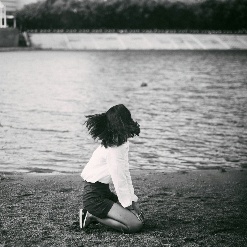 grayscale photography of woman beside body of water