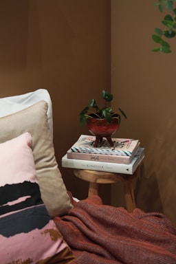 A cozy corner featuring a stack of colorful quilted cushions and a memory foam lumbar pillow on a rustic wooden bench.