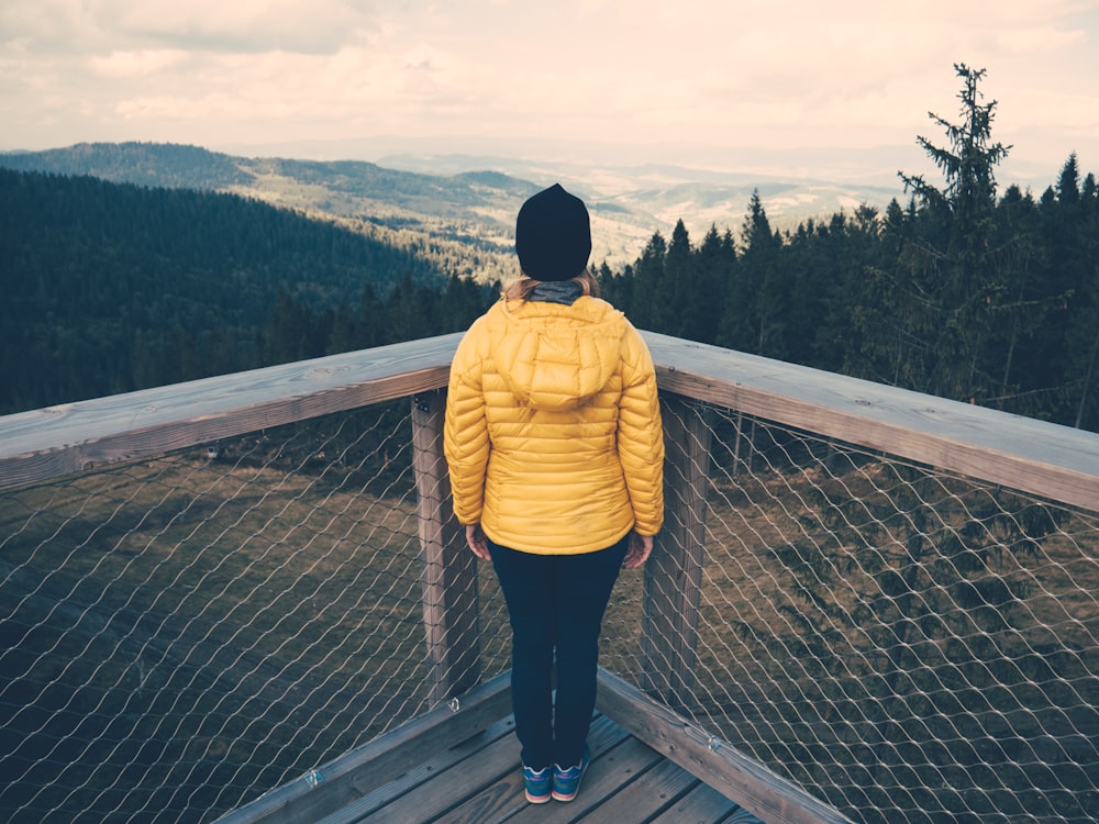 person standing facing towards overview trees and mountains