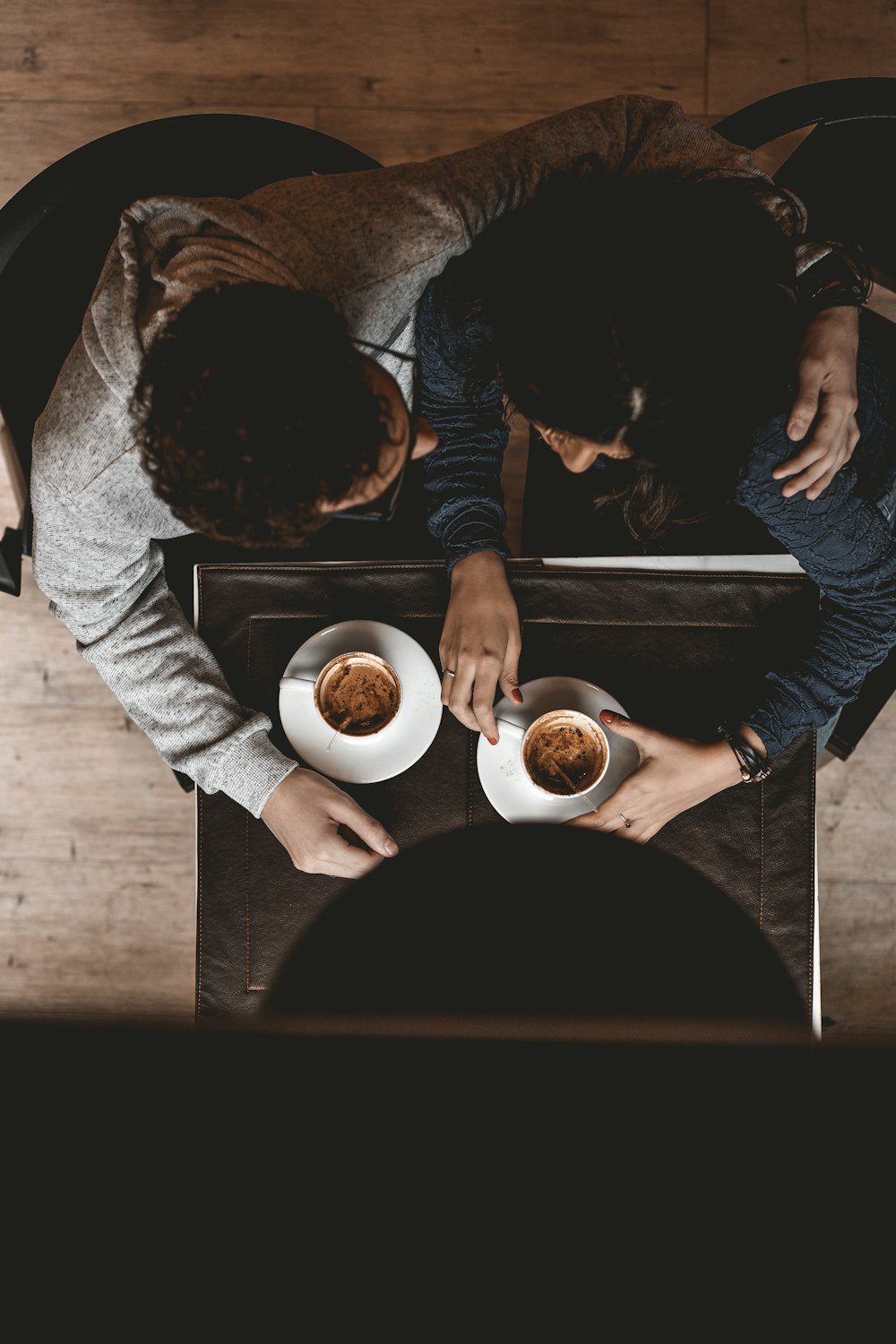 Hombre y mujer sentados en el suelo mientras sostienen tazas sobre la mesa