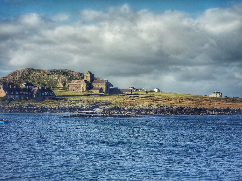 houses near green field viewing calm sea under white and gray skies