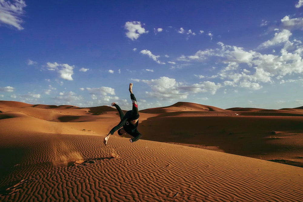 person doing somersault in desert during daytime