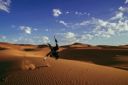 person doing somersault in desert during daytime in Erg Chebbi Morocco