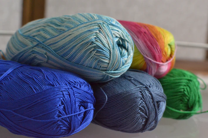 A colorful assortment of yarn skeins in pastel shades neatly arranged on a wooden table.