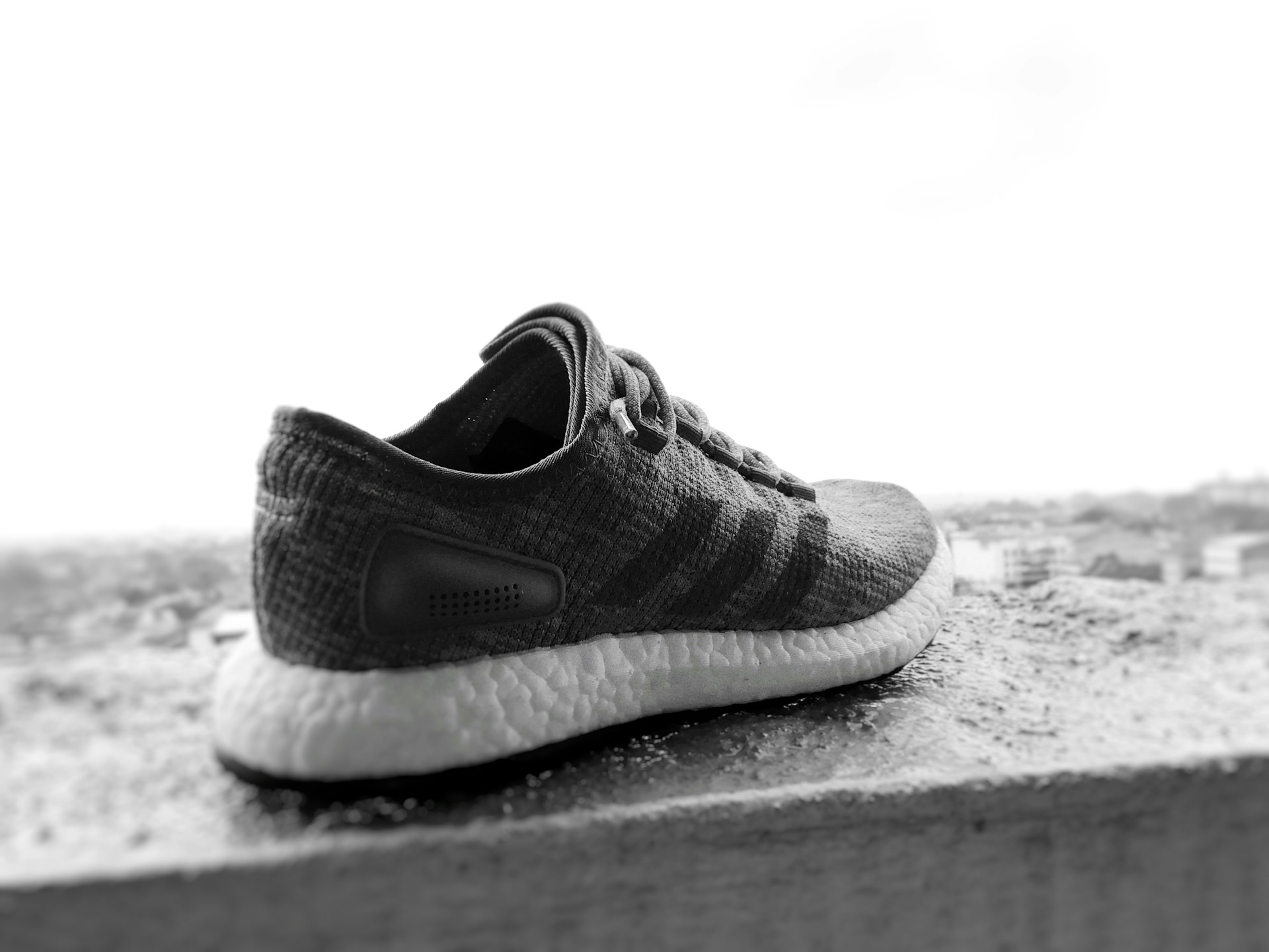 An artistic display of Lumina Apparel's signature sneakers resting on a concrete ledge, with the city skyline softly blurred in the background.