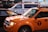 A yellow taxi is parked on the street, reflecting the bright lights of the surrounding urban environment. Nearby is an NYPD police vehicle, indicating a busy city setting.