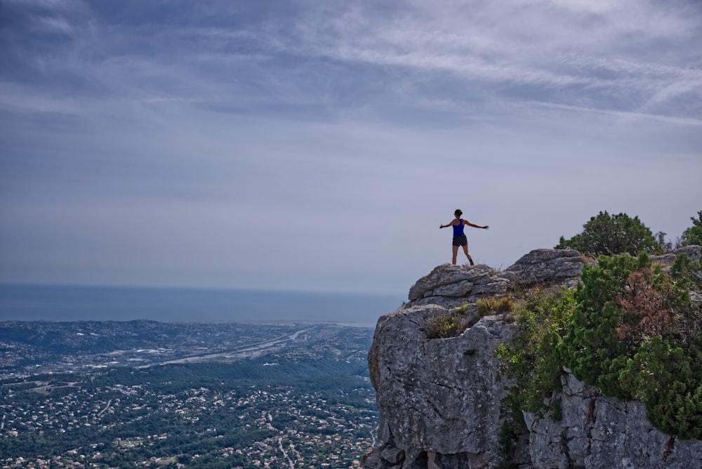 woman standing on cliff overlooking city during daytime