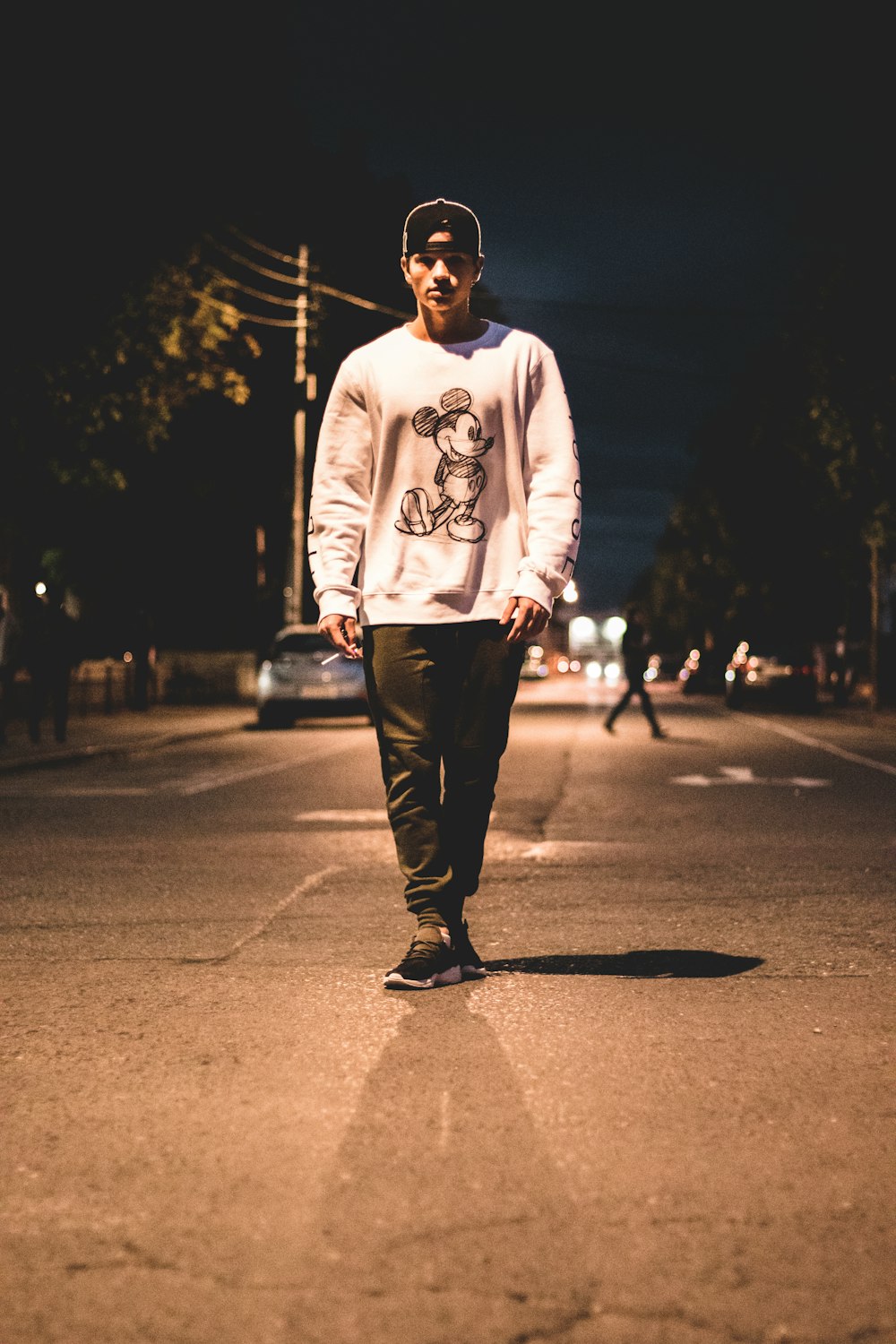 man standing in the middle of road during nighttime