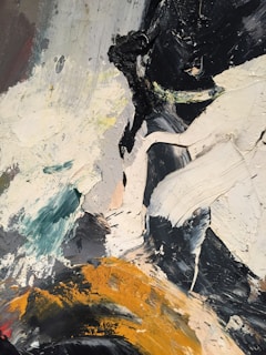 An abstract painting with layered, thick brushstrokes featuring swirls and patches of various colors including black, white, teal, and mustard yellow. The textures are rough and uneven, contributing to a dynamic composition.