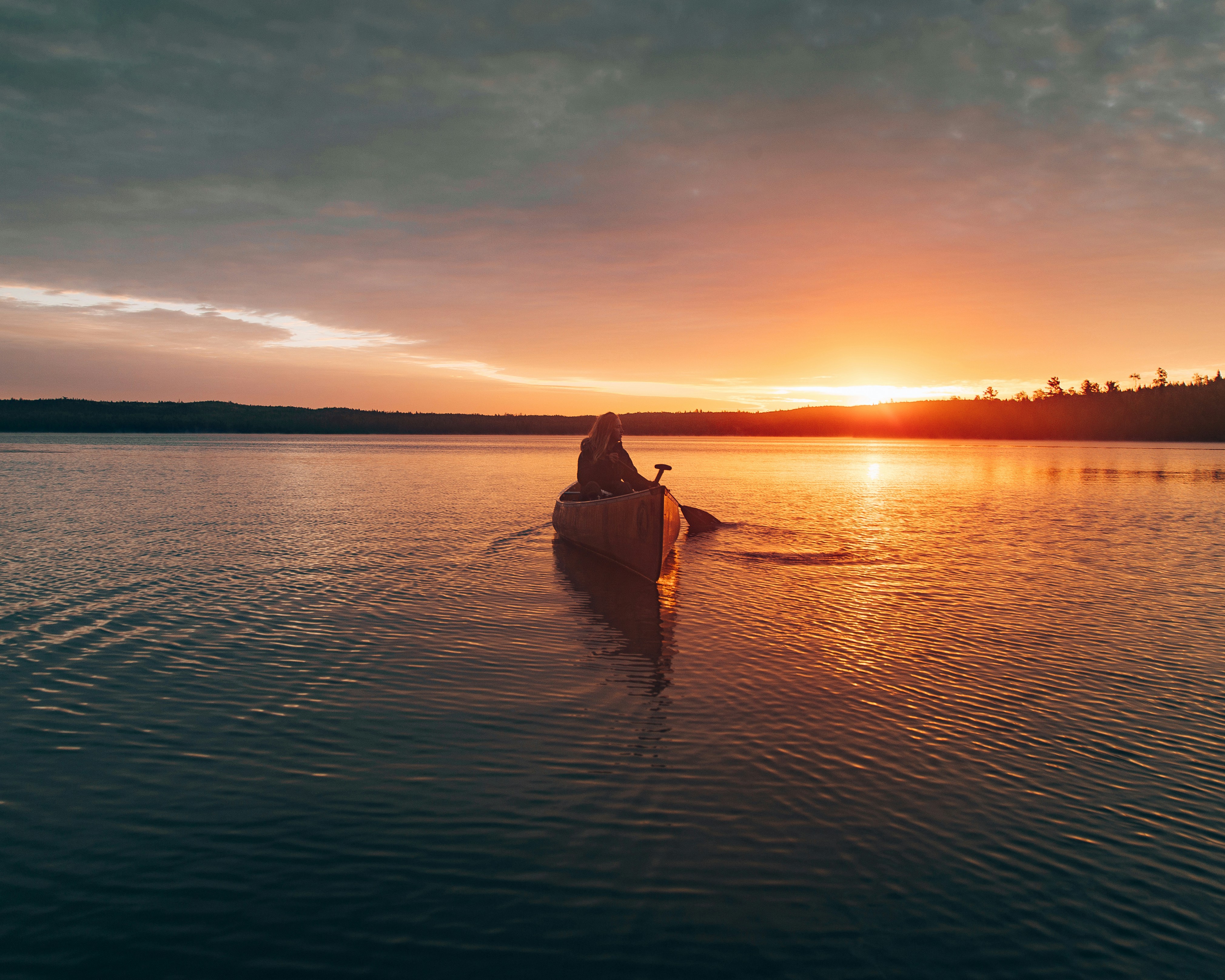 person sailing canoe during sunset