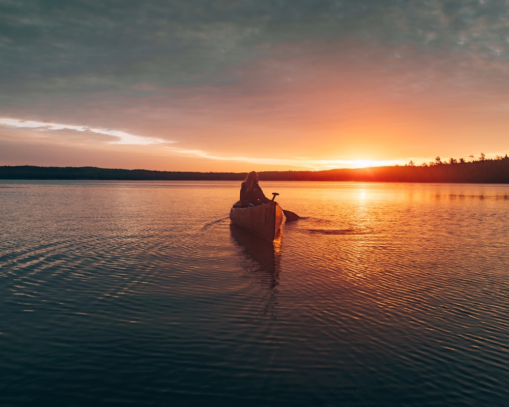 Persona navegando canoa durante la puesta del sol