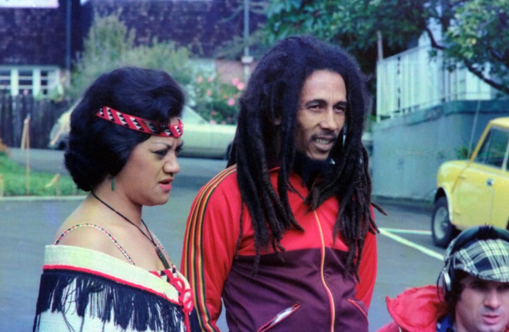Bob Marley standing beside woman during daytime