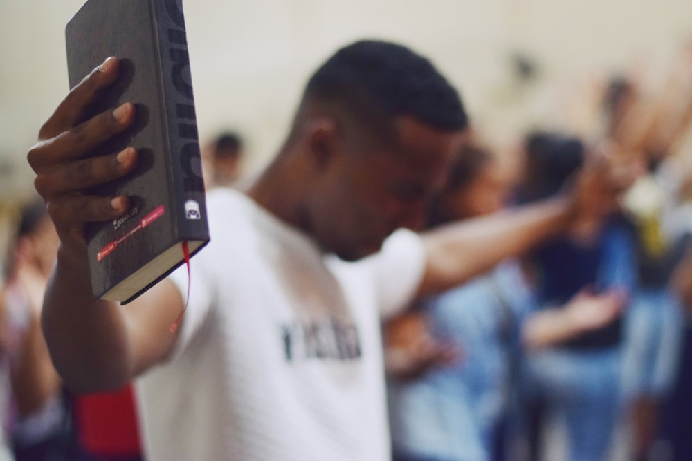 photographie de mise au point sélective d’un homme tenant la Sainte Bible