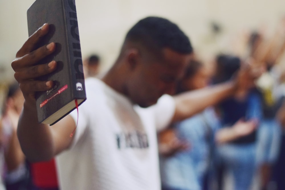 selective focus photography of man holding Holy Bible