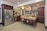 A modern kitchen features sleek stainless steel appliances, including a double-door refrigerator and a farmhouse sink. Dark wood cabinetry contrasts with the light-colored stone countertops and backsplash, creating a warm and inviting atmosphere. The center island is made of wood with shelves below and is topped with a cutting board. Various kitchen items and decorations, such as wine bottles, a mixer, and spice jars, are neatly arranged around the space.