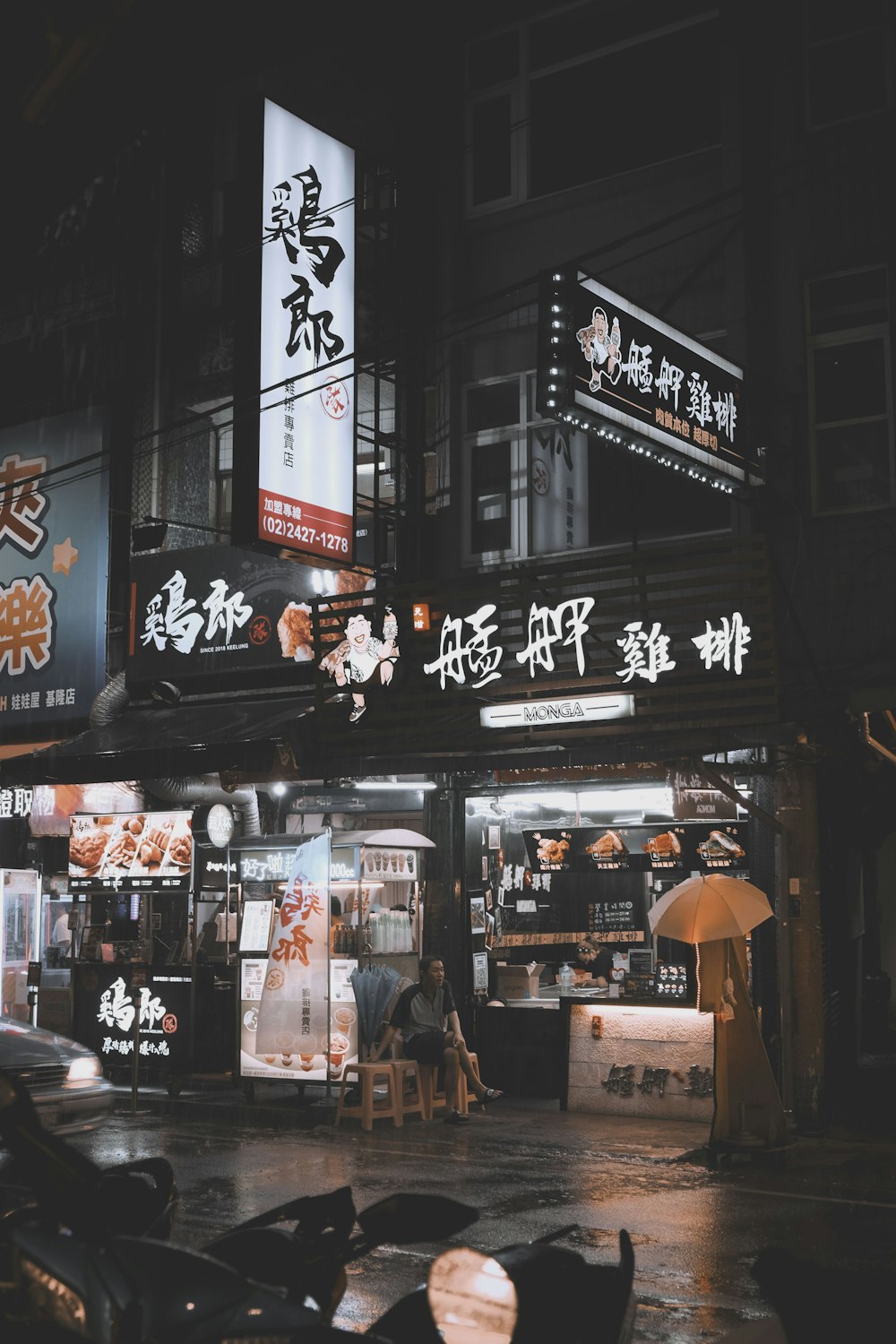 man in gray top sitting on chair beside store facade