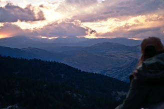 A solo traveler admiring a breathtaking mountain landscape at sunset.