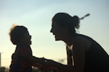 A silhouette of a smiling adult and a child facing each other, capturing a moment of joy and connection in the soft glow of twilight.