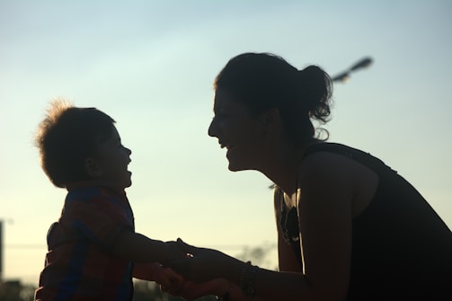 A silhouette of a smiling adult and a child facing each other, capturing a moment of joy and connection in the soft glow of twilight.